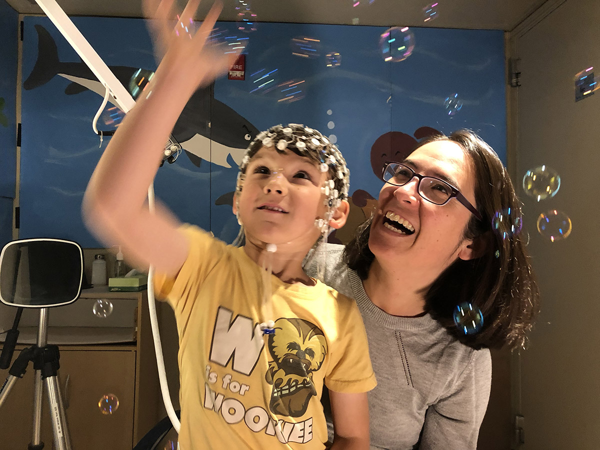 Dr Wilkinson and son wearing EEG machine look at water bubbles in the lab
