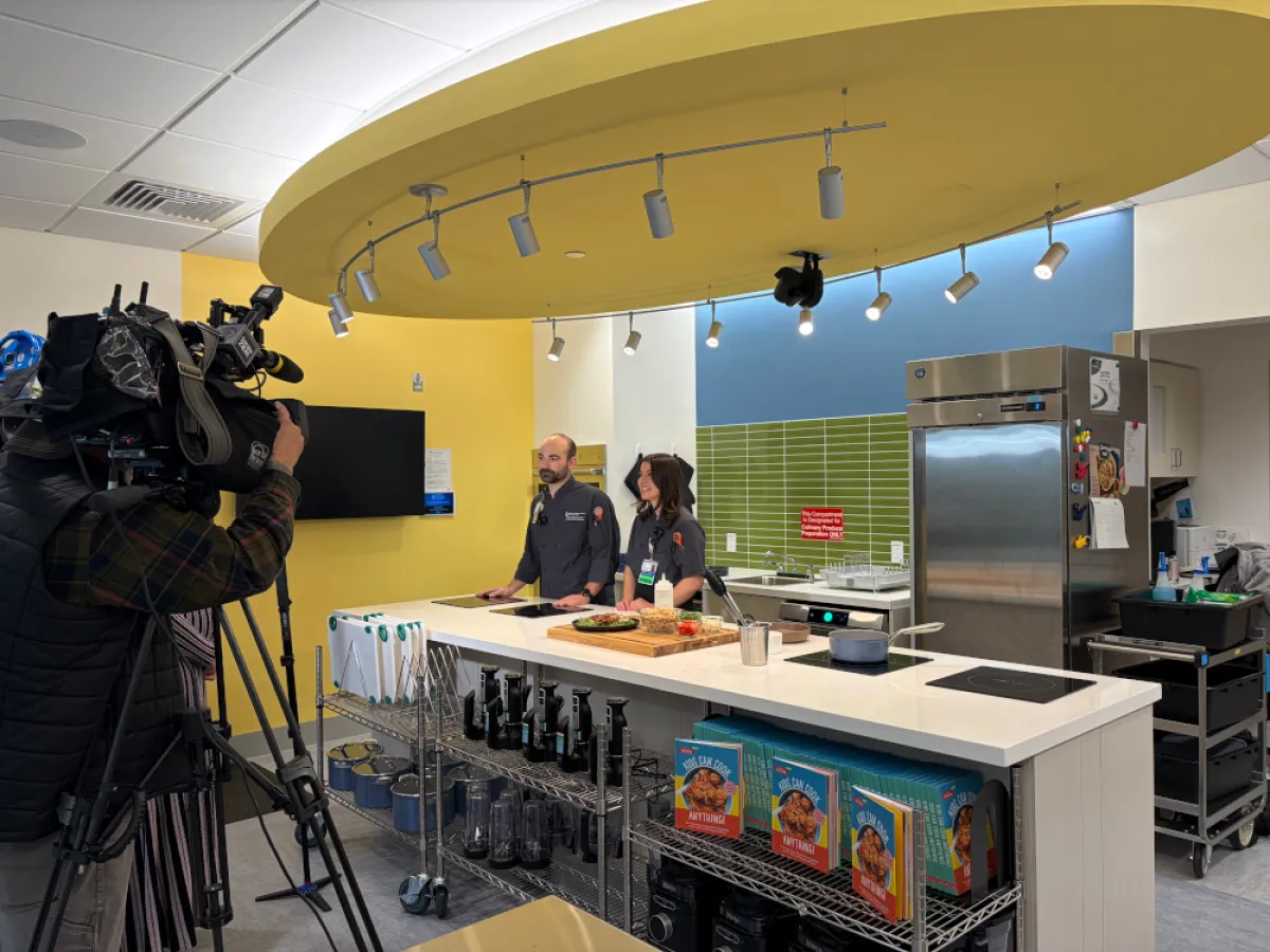 Camera crew films two adults standing behind kitchen island