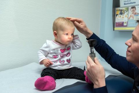 pediatrician shining a light into a baby's eyes