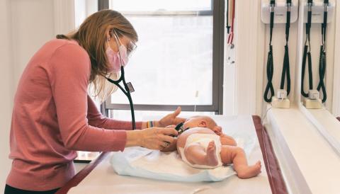 a baby on a table being examed by a doctor with a stethoscope