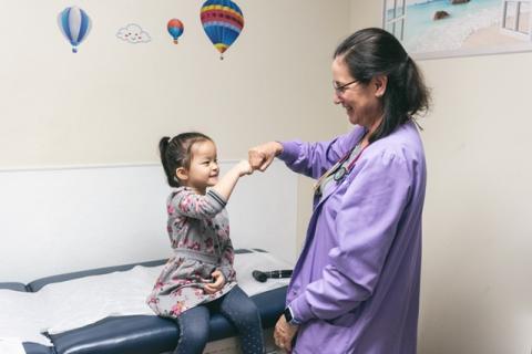a young girl fistbumping with a pediatrician