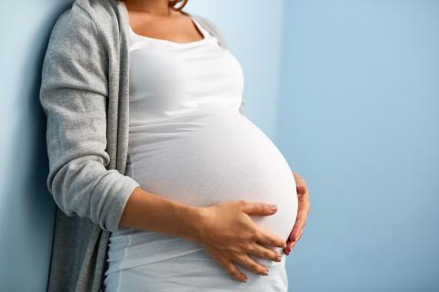 Pregnant woman holds stomach