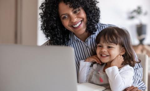 Woman and girl sit at laptop