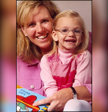 girl with glasses reading book with her mom
