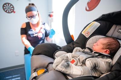 Baby sits in car seat awaiting an examination