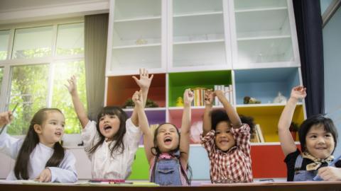 Children smile while raising their arms