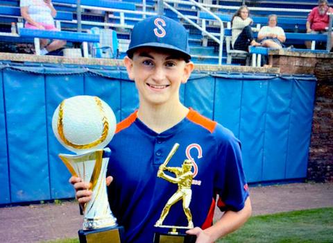 Baseball player in uniform holds two trophies