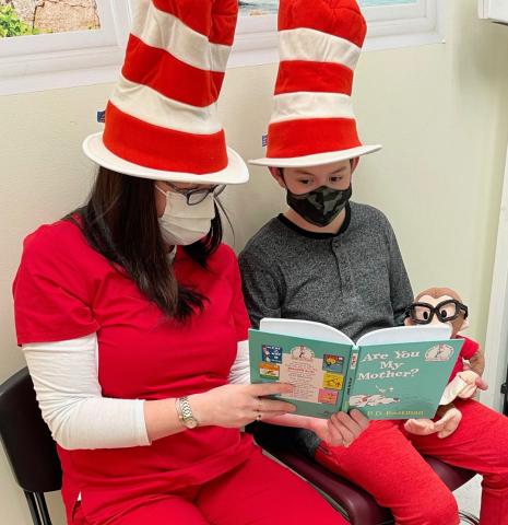 a woman in a cat in the hat hat reading to a boy