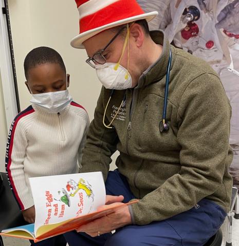 doctor wearing a cat in the hat hat reading to a boy