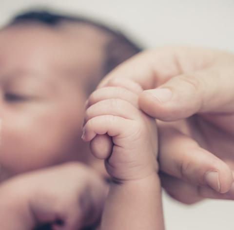 baby holding a person's finger