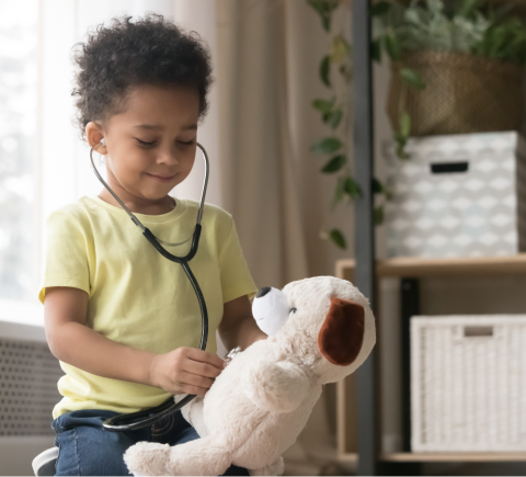 young kid using a stethoscope on teddy bear