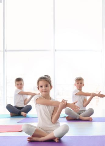 young children stretching their arms on yoga mats