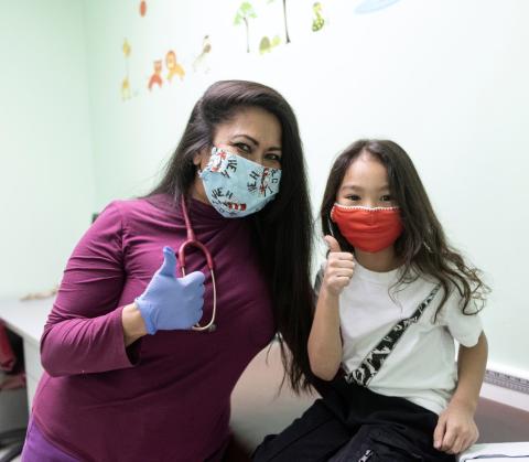 Female clinician and young girl give thumbs up