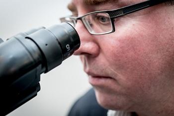 A man looks through a microscope.