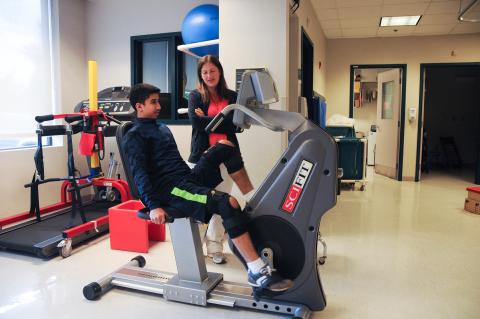Clinician works with patient on exercise machine