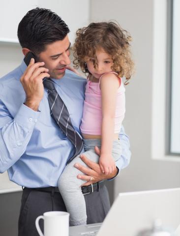 Father holds daughter while speaking on the phone