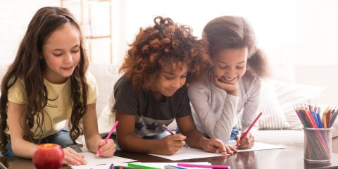 Smiling girls of different backgrounds draw on paper