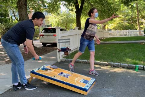Two lab members play corn hole outdoors.
