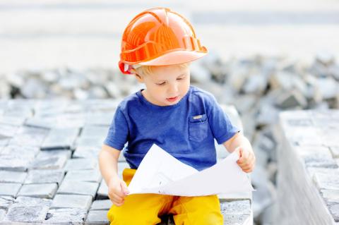 kid with a hardhat looking at schematics