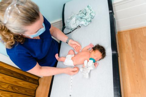an infant on an exam table with a pediatrician