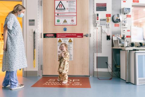 Young girl enters MRI suite and is greeted by clinician