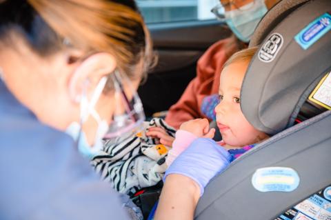 a woman doctor checking a car seat with a child in it