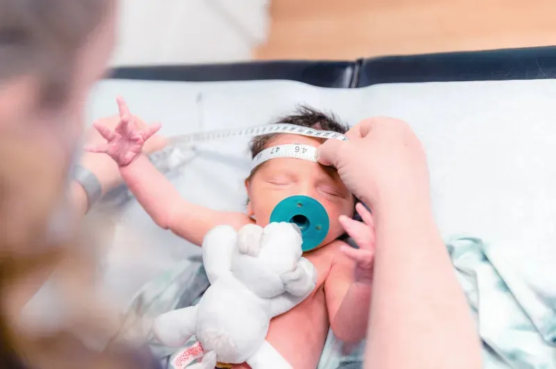 a pediatrician measuring a newborn head