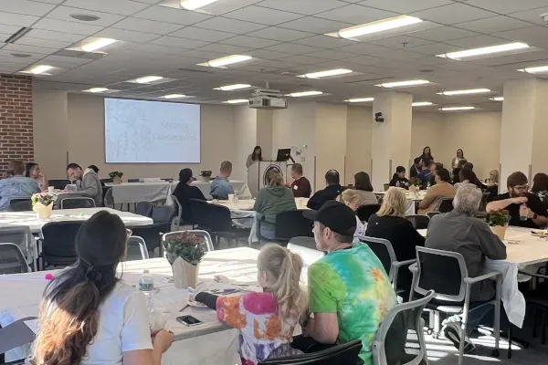 Room with many people in it viewing presentation on large screen