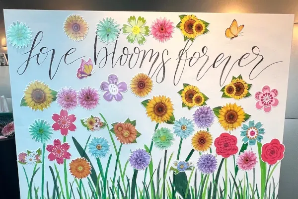 Painting: Text: “Love blooms forever.” Along with images of various types of flowers