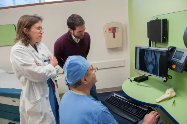 Three clinicians gather around a monitor to review medical imagery
