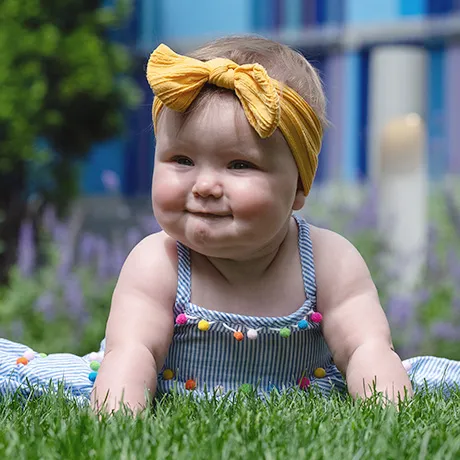 Young girl with bow in hair lays on grass