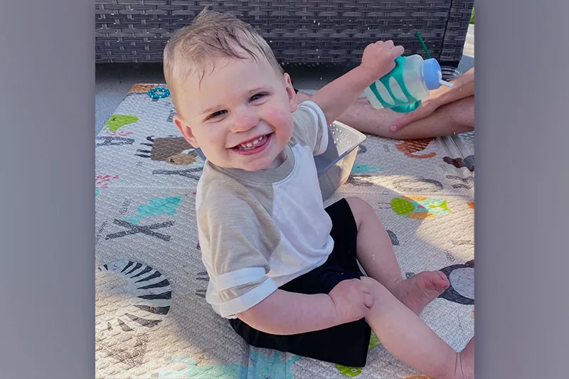 Young boy sits on a blanket on the floor