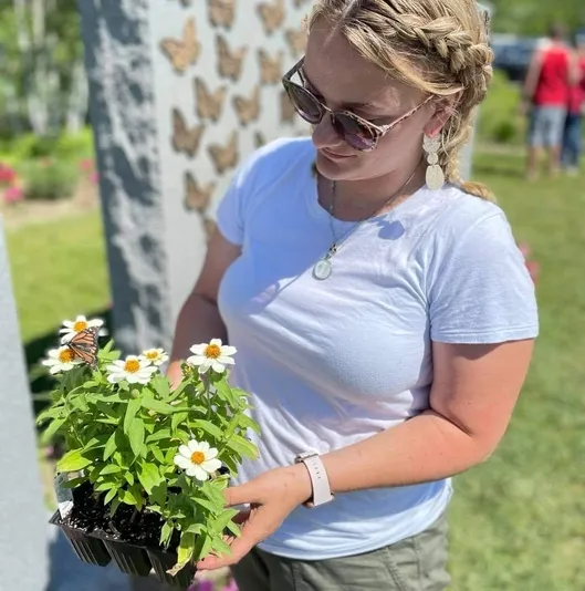Woman holds basket of flowers in front of headstone