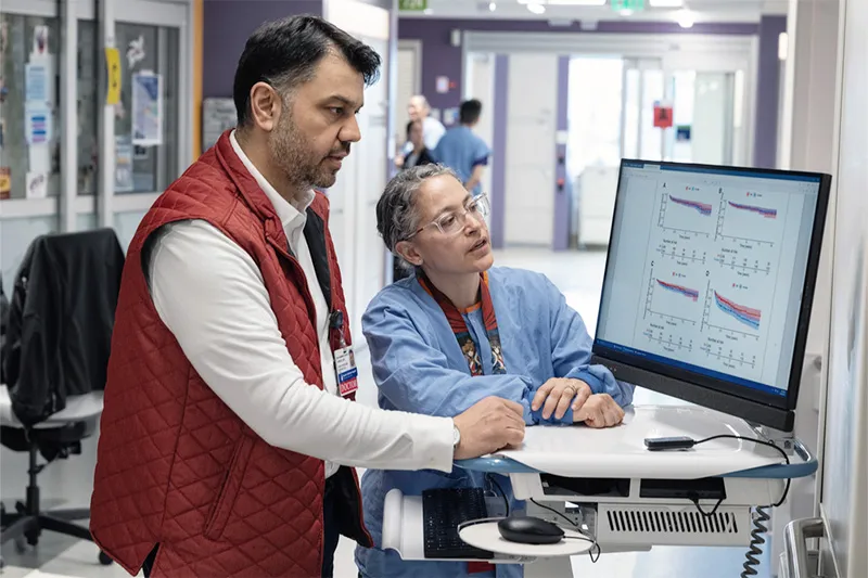 Two doctors review study results on a computer screen.