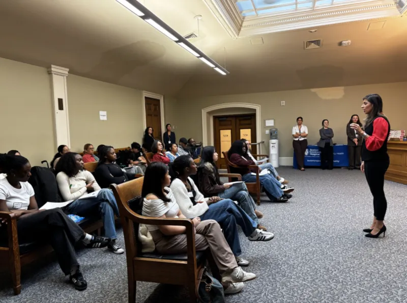 Woman speaks while standing in front of many teenagers during a group session.