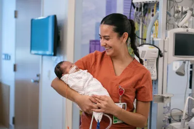 Hospital employee holds baby swaddled in blanket