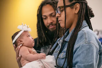 Mom holds baby, father looks on