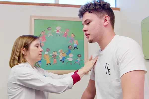 Clinician holds stethoscope against chest of teen male