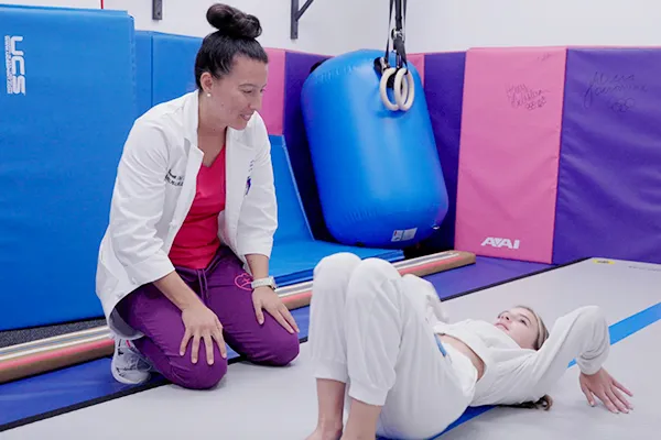 Clinician works with patient during exercise as patient lay on floor