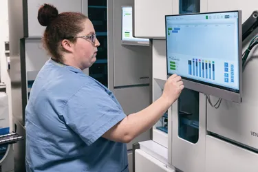Woman in scrubs checking health information on a computer screen
