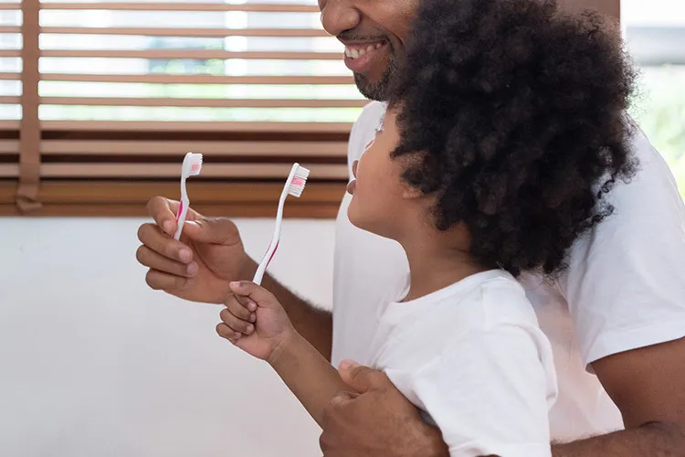 Child and father brush their teeth at the same time