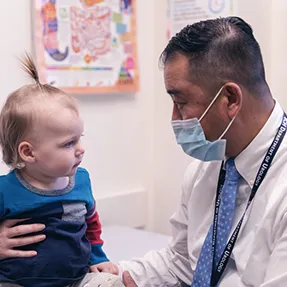 Doctor speaks with young patient who is sitting on exam room table