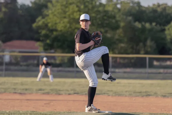 Teen boy throws pitch off baseball field's mound