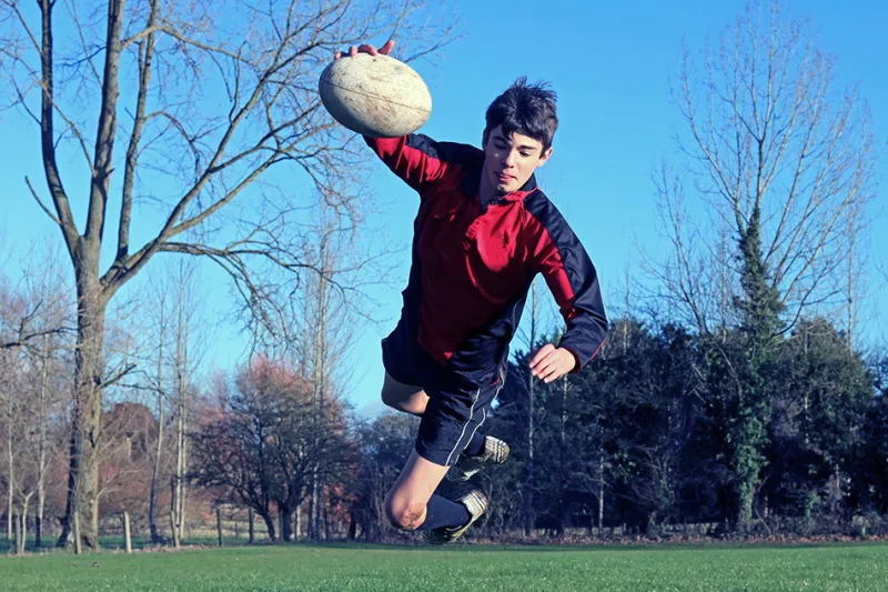 Male rugby player dives toward end zone with ball stretched out