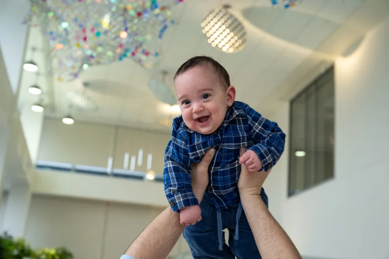 Toddler held up high in the air by an adult with unstretched arms
