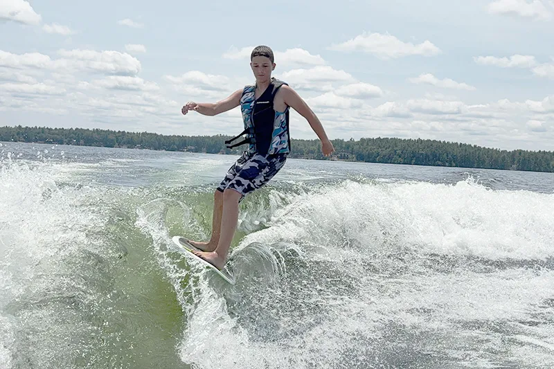 Teen boy travels on surfboard in body of water
