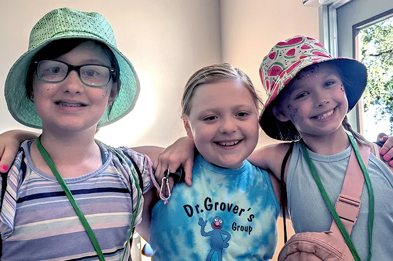 Three young girls embrace and pose for the camera