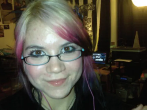 Young woman with streaks of color in hair and wearing glasses poses at camera