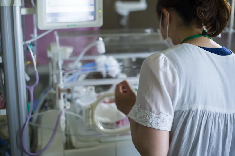 A mom with her back to the camera looks at her baby in the nicu.