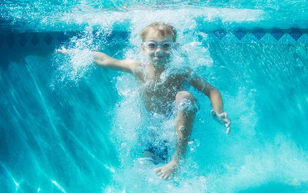 Boy swims in pool.